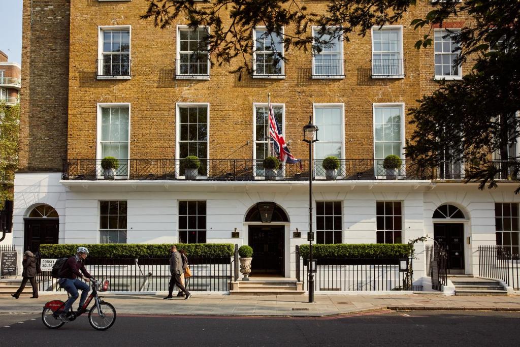 a man riding a bike in front of a building at Dorset Square Hotel, Firmdale Hotels in London