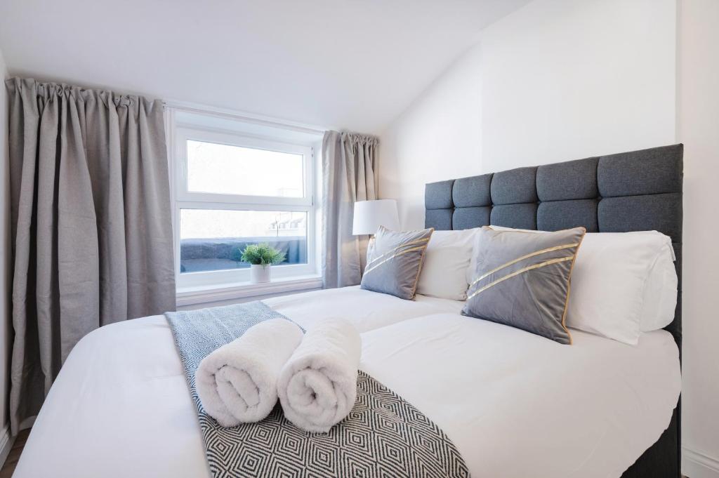 a bedroom with a large white bed with towels on it at London Paddington Station Apartments in London