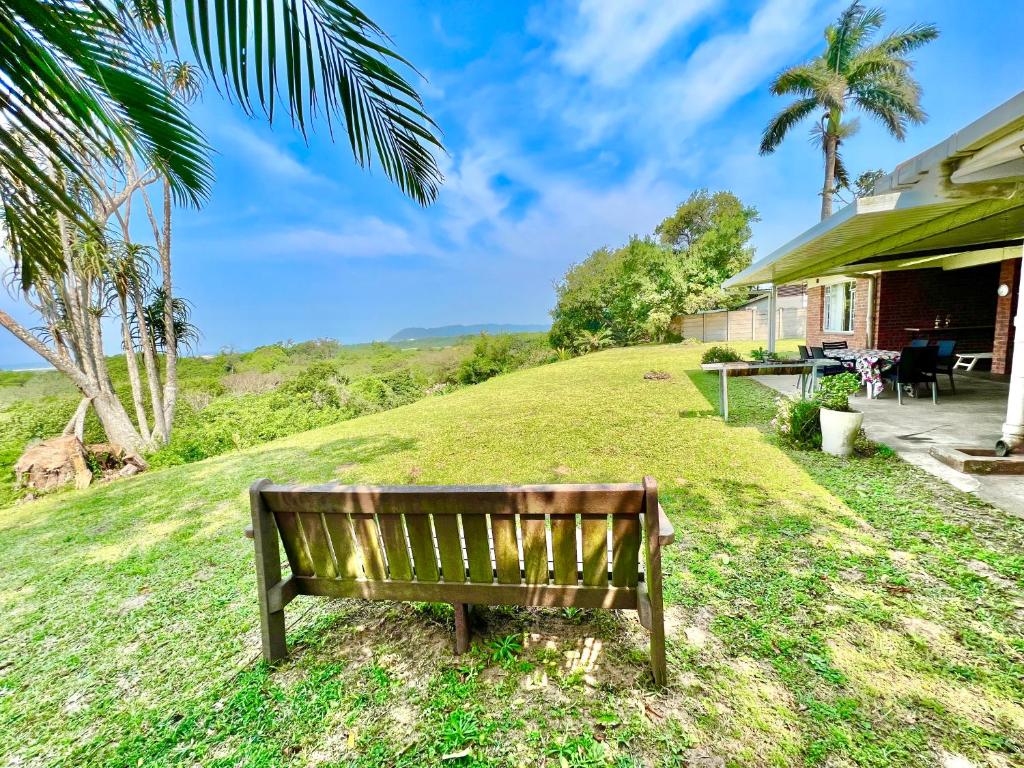 a bench sitting in the grass next to a house at St Lucia Holiday Cottage in St Lucia