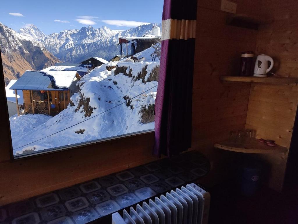 a view of a snow covered mountain from a window at Poppy Resorts Auli in Joshīmath