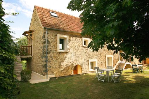 une maison en pierre avec une table et des chaises dans la cour dans l'établissement S2-gite sevin, à Saint-Forget