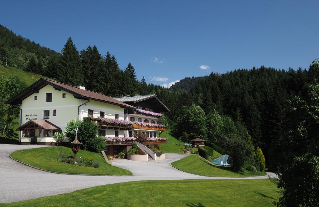 a large white building on a hill with trees at Alpenapartments Unterschlag in Annaberg im Lammertal