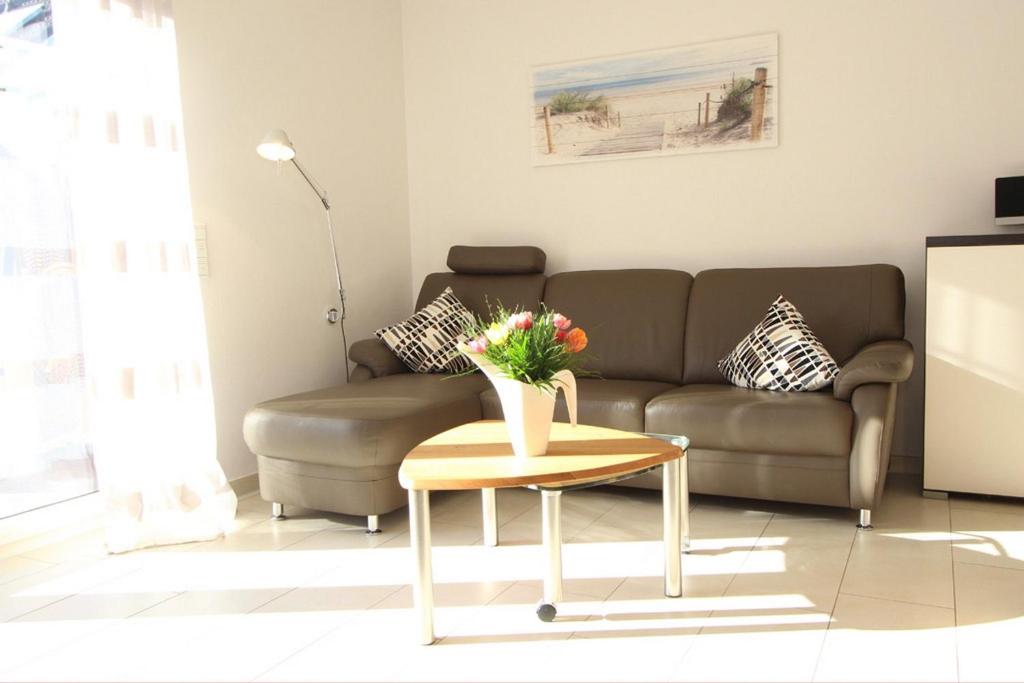 ein Wohnzimmer mit einem Sofa und einem Tisch mit Blumen darauf in der Unterkunft Dünenhäuser Haus 3 in Boltenhagen