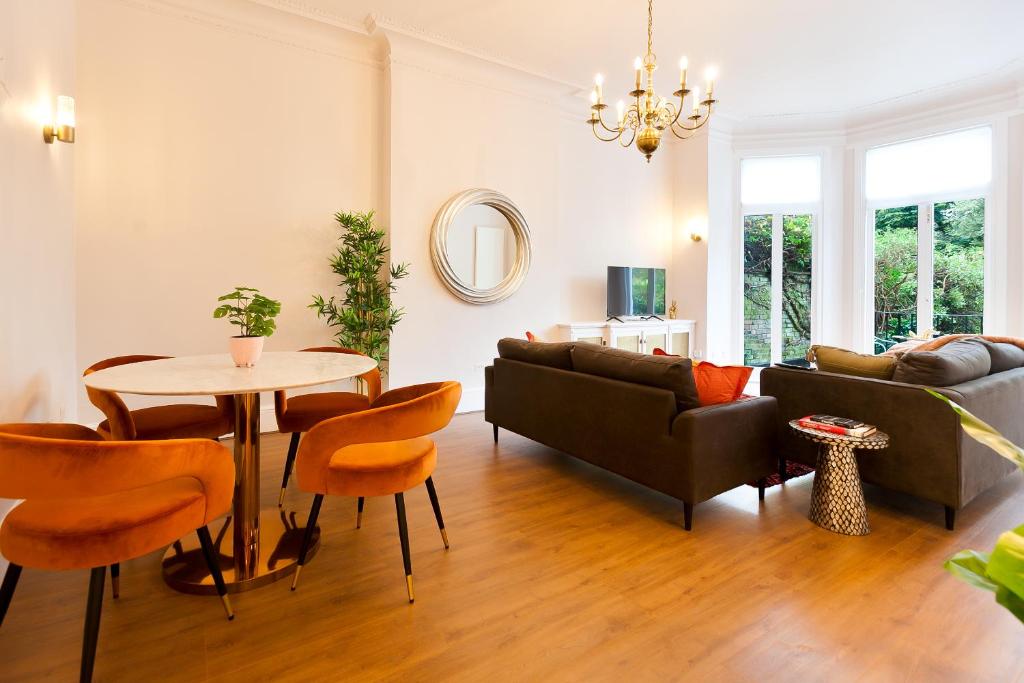 sala de estar con sofá, mesa y sillas en Primrose Hill Apartments en Londres