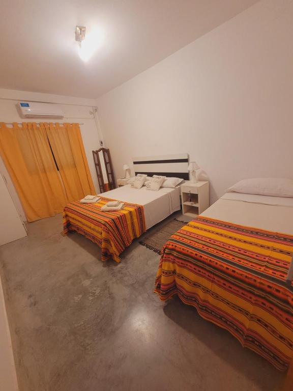 1 dormitorio con 2 camas y mantas de color naranja y amarillo en Departamento Génesis, 1er piso en Chilecito