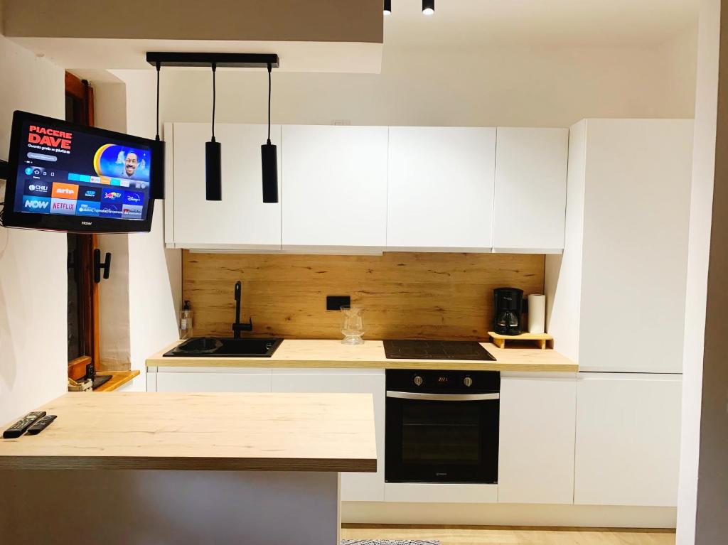 una cucina con armadi bianchi e una TV a schermo piatto di Casalago Holiday Home a Ronciglione