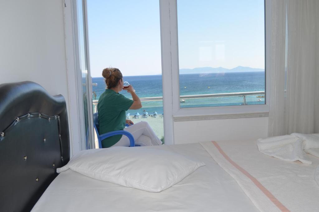a woman talking on a cell phone in front of a window at Yasmin Hotel in Ayvalık