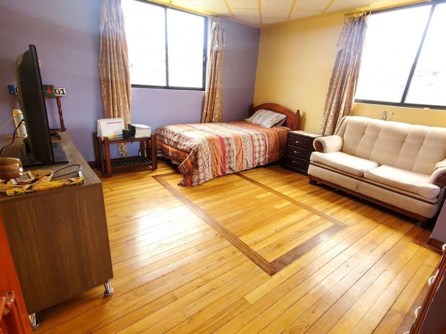 sala de estar con cama y sofá en Suite Hostal El Trébol 2 habitaciones en Latacunga