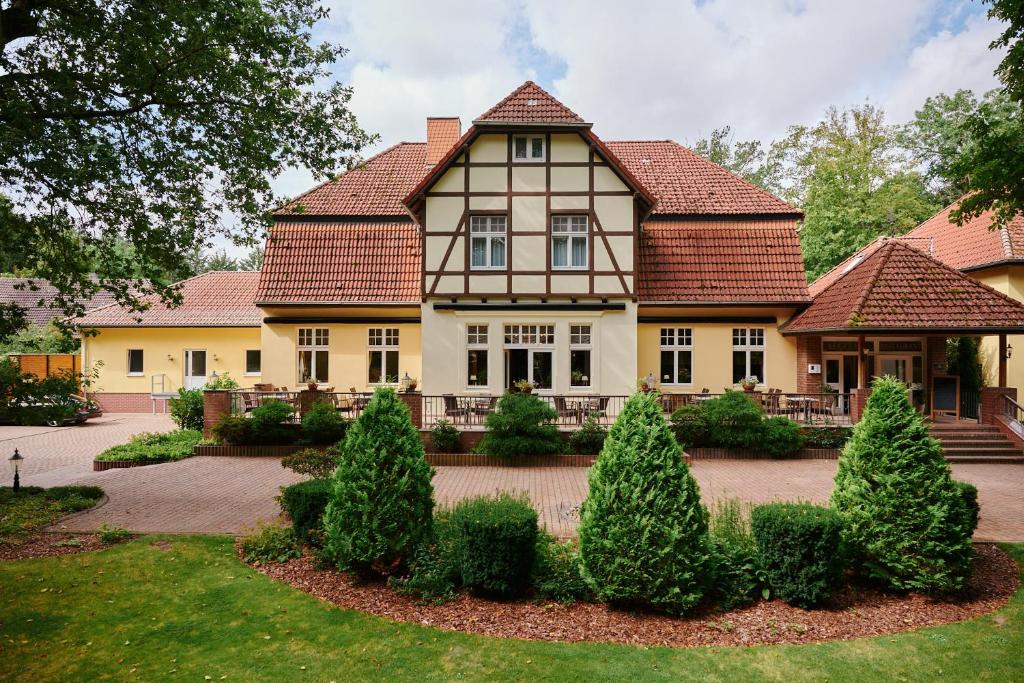 duży dom z drzewami przed nim w obiekcie Waldhotel Forsthaus Hainholz w mieście Pritzwalk