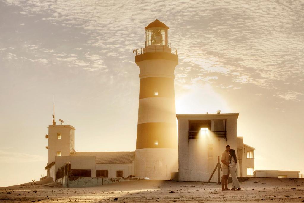 un hombre parado frente a un faro en Cape Recife Lighthouse Luxury Villa, en Port Elizabeth