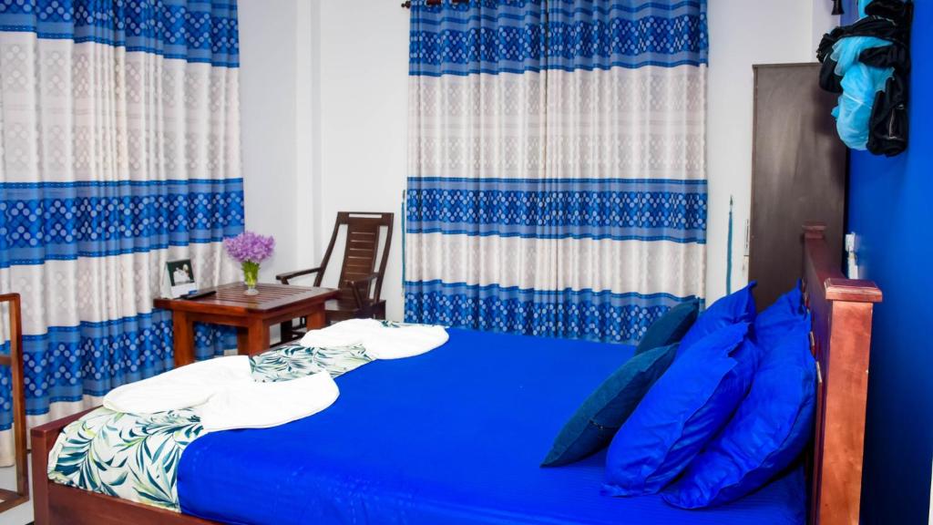 een slaapkamer met een blauw bed met blauwe kussens bij Yala Grand Homestay in Tissamaharama