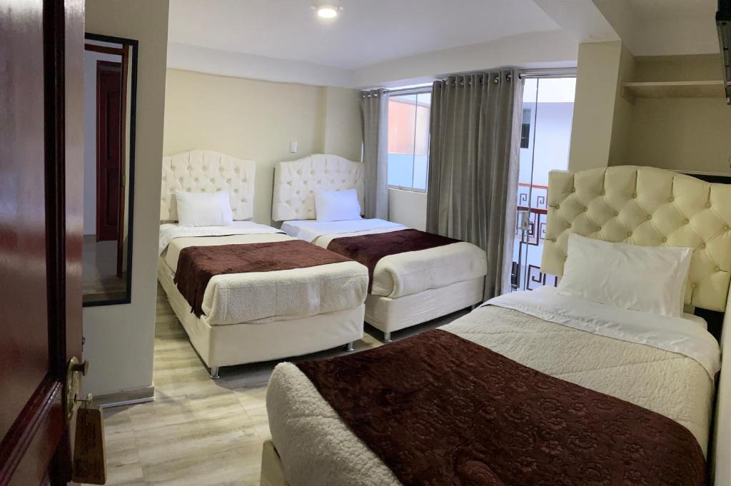 a hotel room with two beds and a balcony at ANDEAN VALLEY HOTEL in Cusco