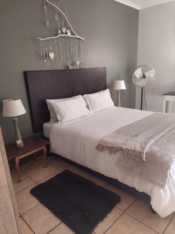 a bedroom with a large white bed and two lamps at Sophia’s Cottage in Cape Town