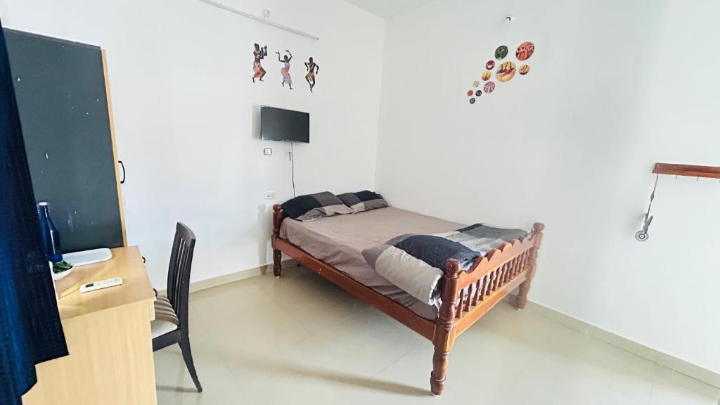 a bedroom with a bed and a desk with a monitor at Casa De Neel in Puducherry