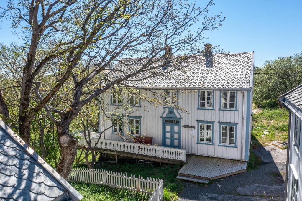 a white house with a porch and a tree at Lofoten Budget Hostel in Å