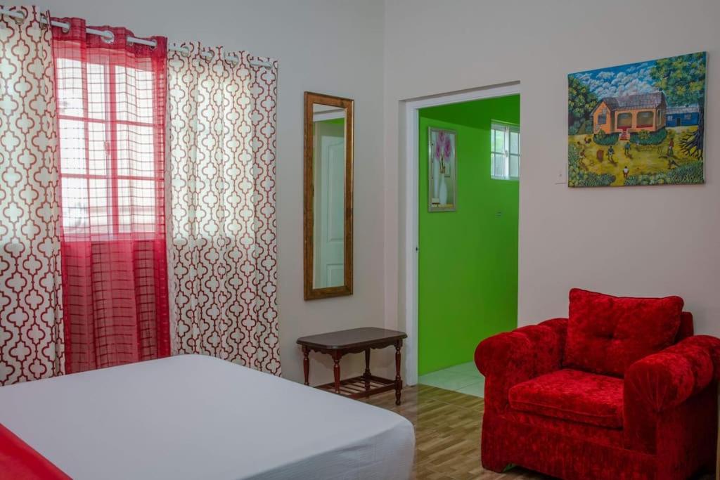 een slaapkamer met een bed en een rode stoel bij Savan Suite - Caribbean Estates - Gated Community in Portmore