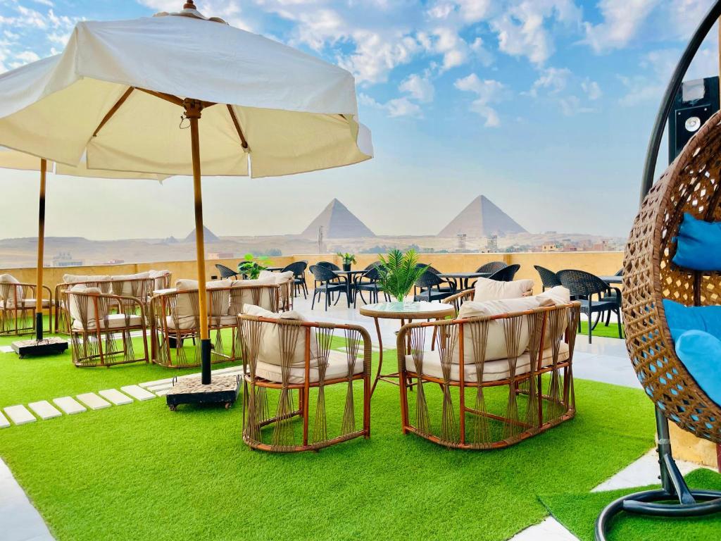 un gruppo di tavoli e sedie con ombrellone di Palm Pyramids View INN a Il Cairo