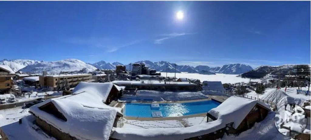 ośrodek wypoczynkowy pokryty śniegiem z górami w tle w obiekcie Studio Alpe d'huez w mieście LʼHuez
