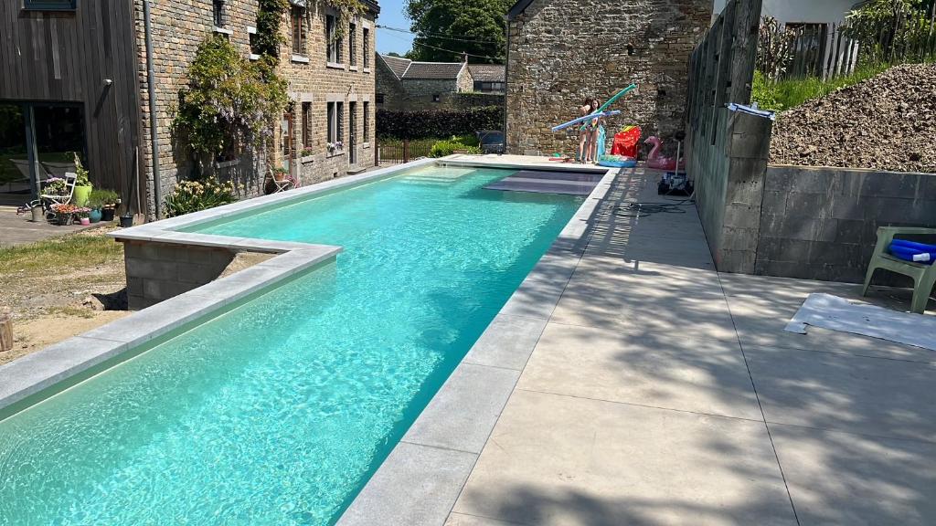 a swimming pool with blue water in a yard at Gite MontBleu - 2 holiday houses - La Laiterie & La Grange in Sprimont