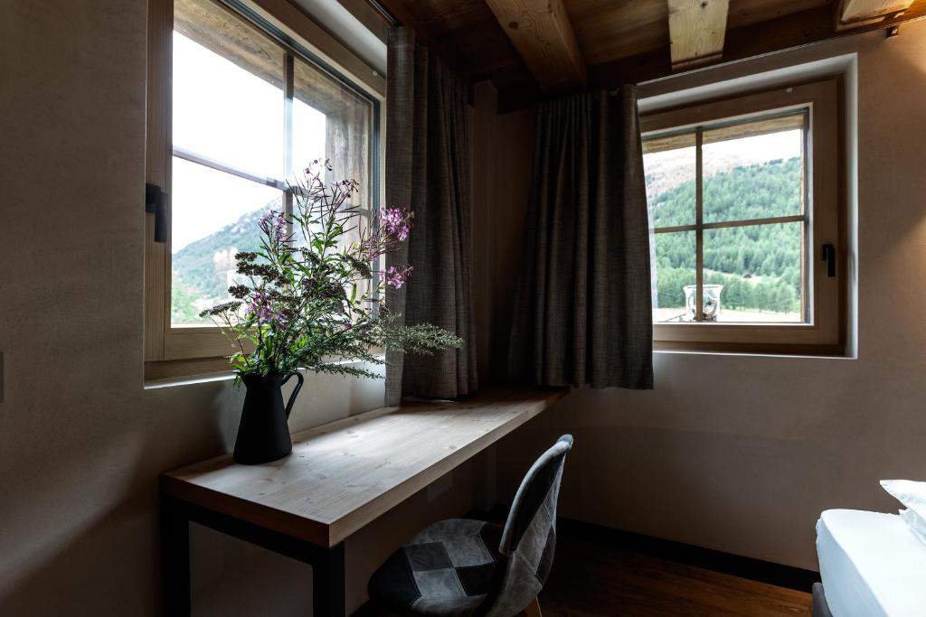 un jarrón de flores sentado en una mesa en una ventana en Snow Villa Genf with Spa, en Livigno