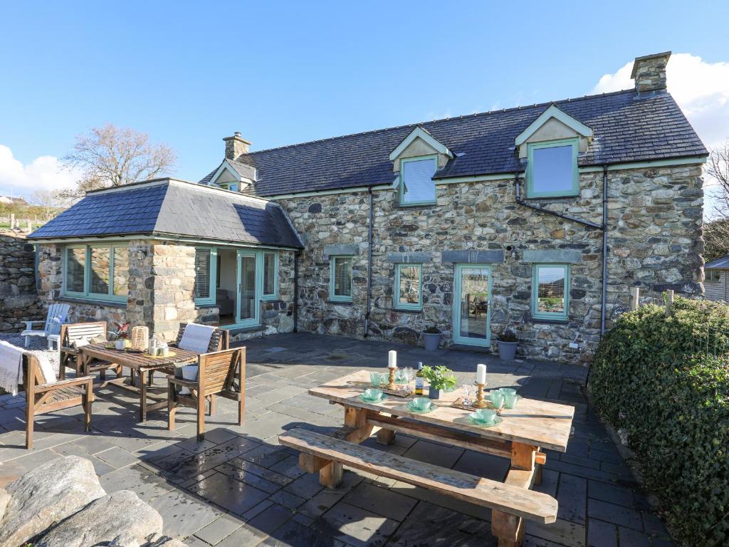 a stone cottage with wooden tables and chairs at Glanrafon in Caernarfon