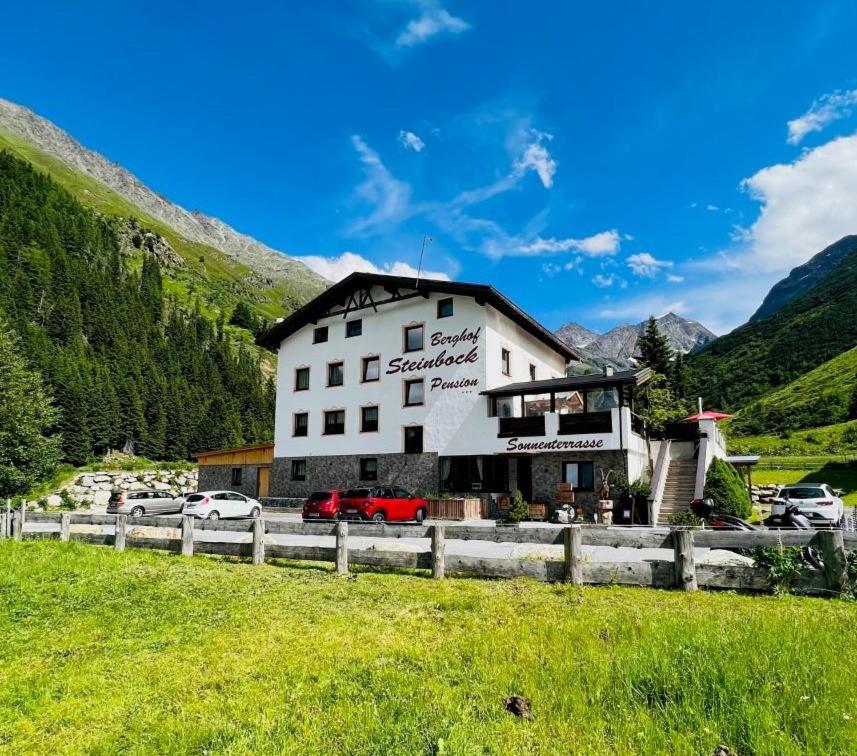 a large white building with cars parked in a field at Apart Berghof Steinbock in Sankt Leonhard im Pitztal