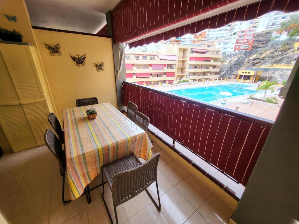 um quarto com uma mesa e uma varanda com uma piscina em Olivia Sunset 2 em Puerto de Santiago