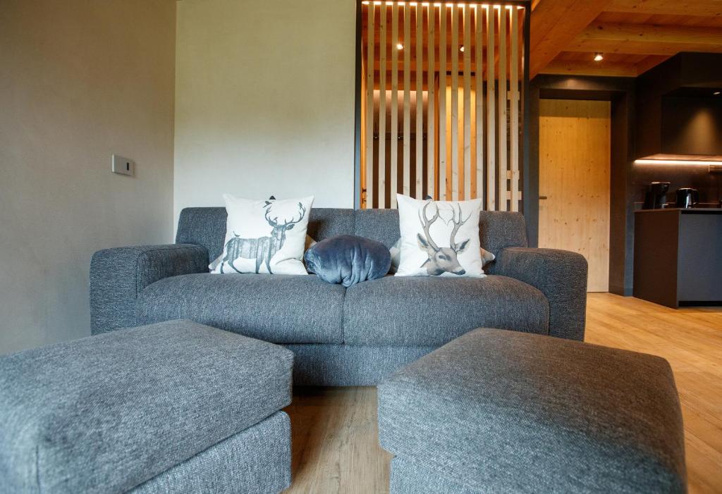 a living room with a blue couch with two deer pillows at Sun Villa Genf Spa - Relax in Livigno