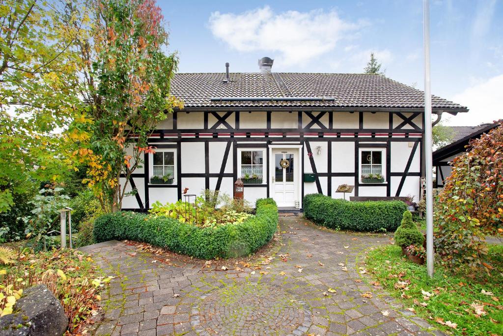 a white and black house with a brick driveway at Ferienwohnung Rotdorn in Schmallenberg