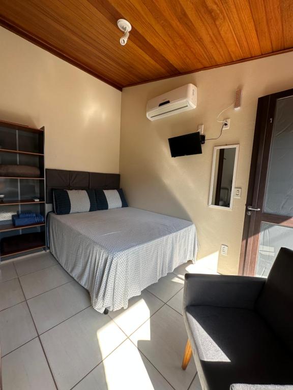 1 dormitorio con 1 cama y TV. en Nascer Do Sol Suites, en Guarda do Embaú
