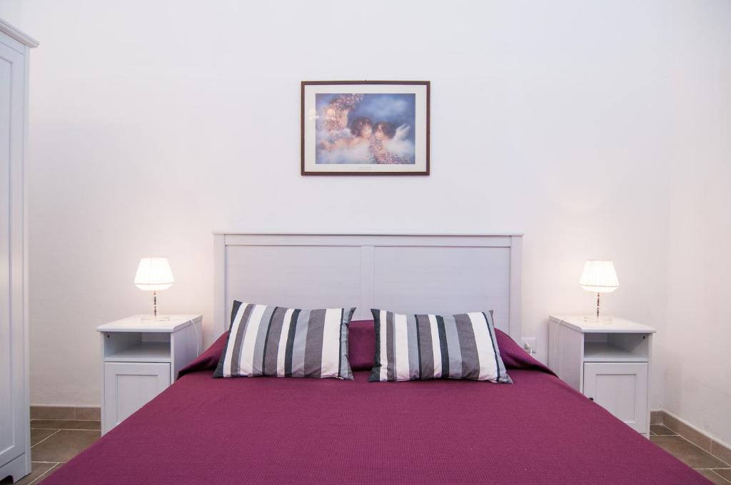 een slaapkamer met een paars bed en 2 nachtkastjes bij Casa vacanze Cristina in Noto