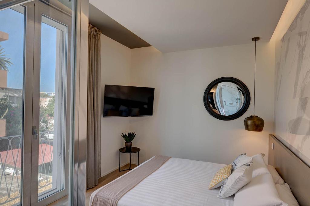 a bedroom with a bed with a mirror and a window at Le Palmette Suites in Cagliari
