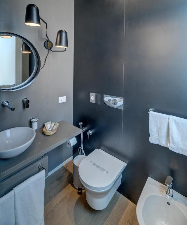 a bathroom with a toilet and a sink and a mirror at Le Palmette Suites in Cagliari