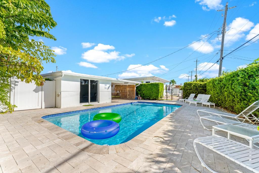 - une piscine dans une cour avec des chaises et une maison dans l'établissement Wonderful 3br Steps To The Beach Wheated Pool, à Fort Lauderdale