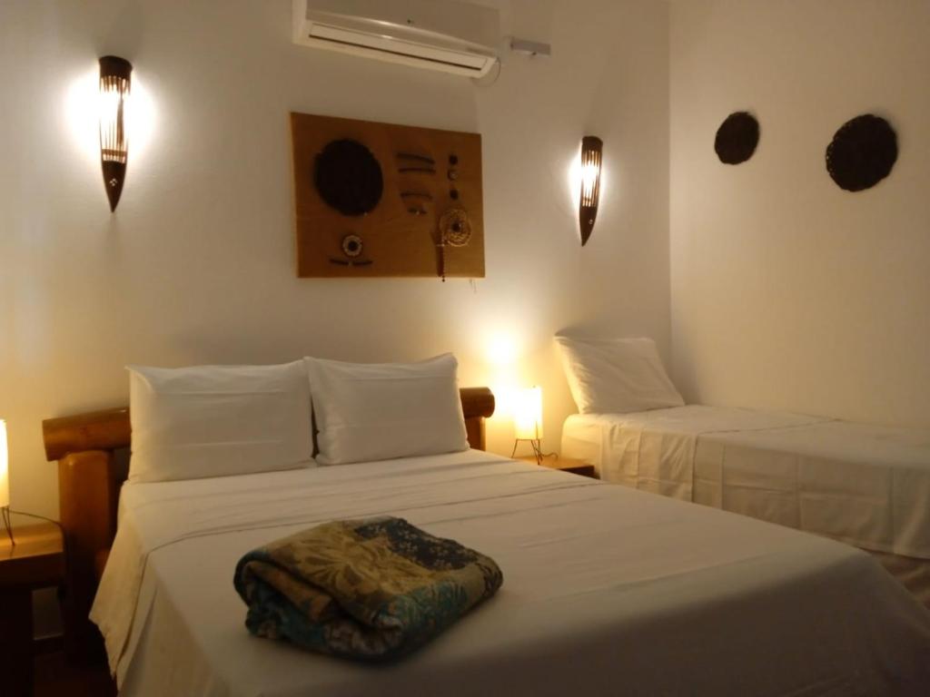 a bedroom with two beds with white sheets and lights at Pousada Chez Loran lagoa do paraiso in Jijoca de Jericoacoara