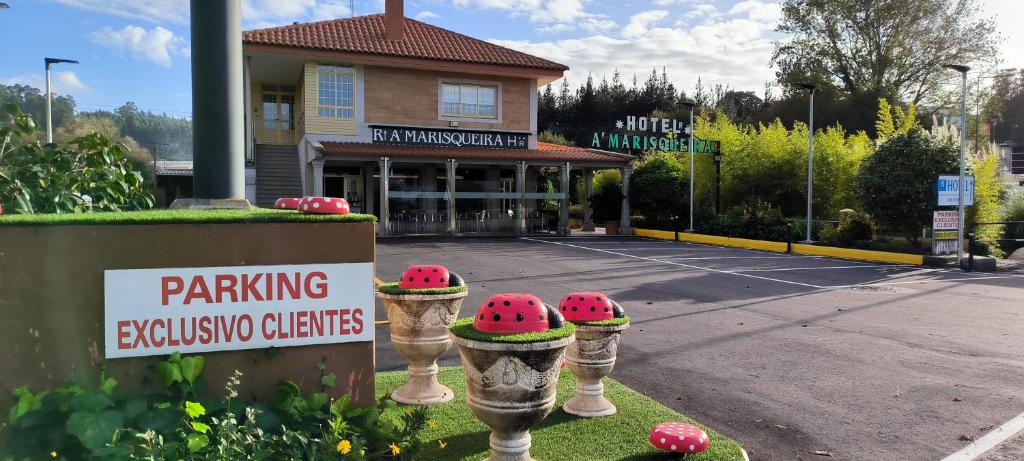 ein Parkgelände mit roten Wanzen vor einem Gebäude in der Unterkunft Hotel A Marisqueira I Aeropuerto A Coruña in Oleiros