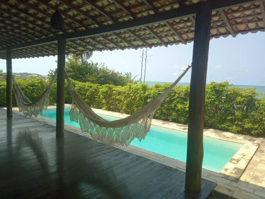 a hammock on a deck next to a swimming pool at A janela do amanhecer in Maxaranguape