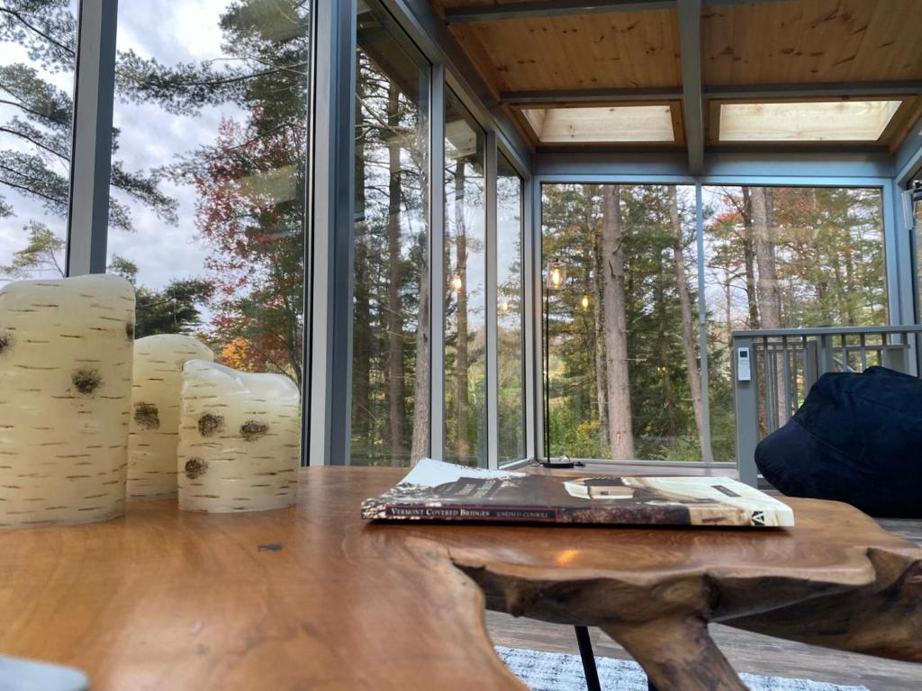 einen Tisch mit Laptop in einem Zimmer mit Fenstern in der Unterkunft Vermont Mirror House in Guilford