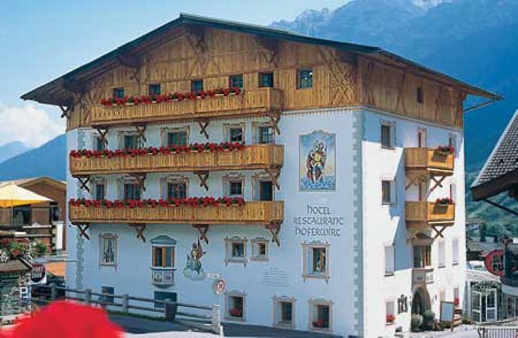 duży biały budynek z drewnianym dachem w obiekcie Hotel Hoferwirt w Neustift im Stubaital