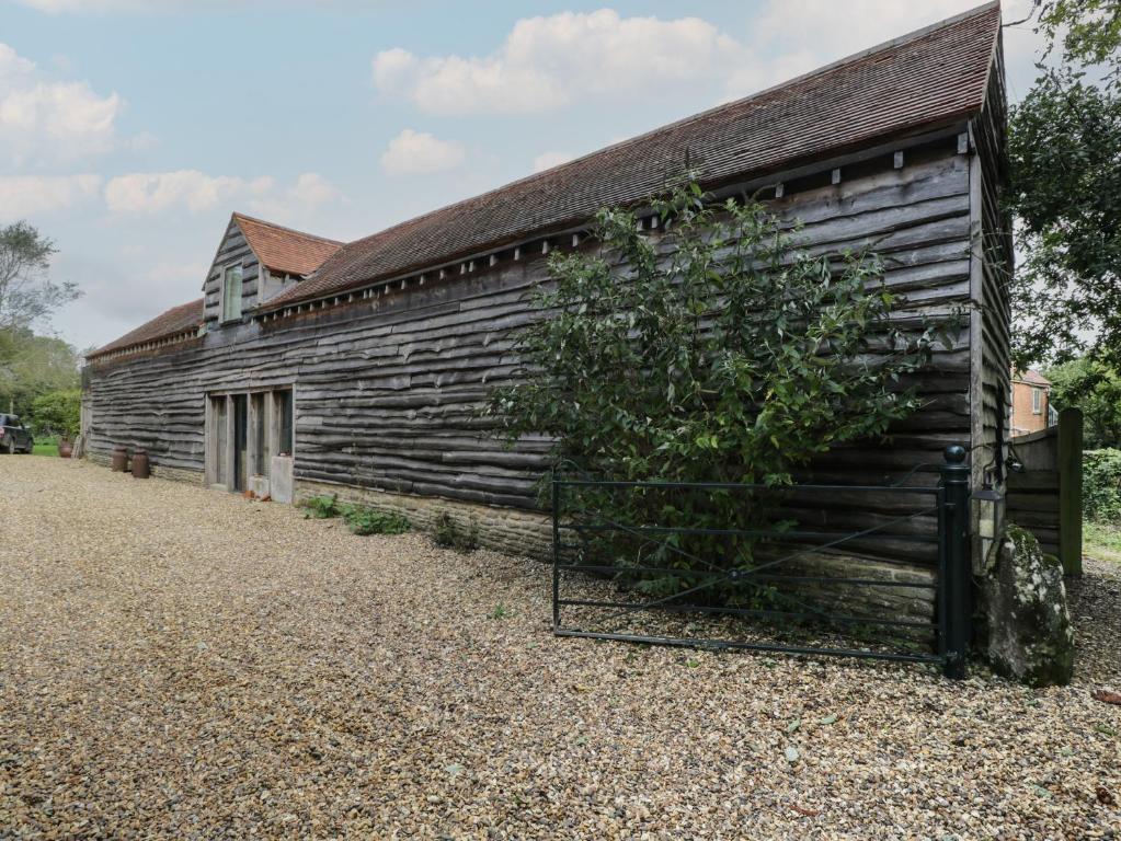 an old wooden building with a tree next to it at Brandeers Long Barn in Malmesbury