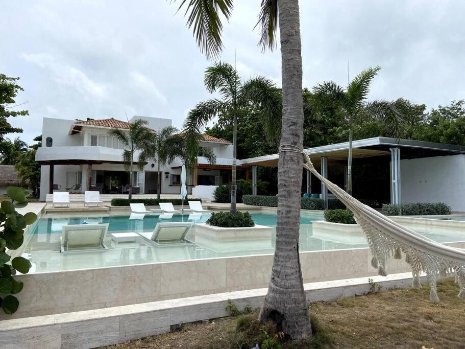 a house with a swimming pool and a hammock in front of it at Villa en Barú con playa privada 6BR in Baru
