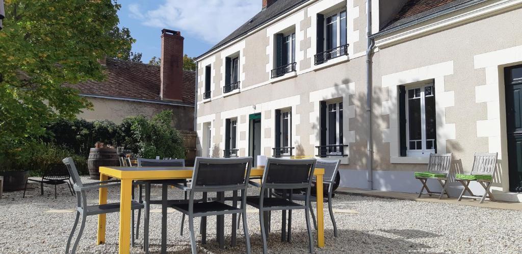 a yellow table and chairs in front of a building at Les hirondelles du moulin in Sassay