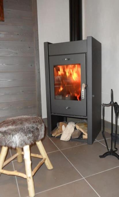 a fireplace with a chair in front of a stove at Chalet Bio Corti 6p. 3 ch proche pistes&#47;commerces in Champagny-en-Vanoise