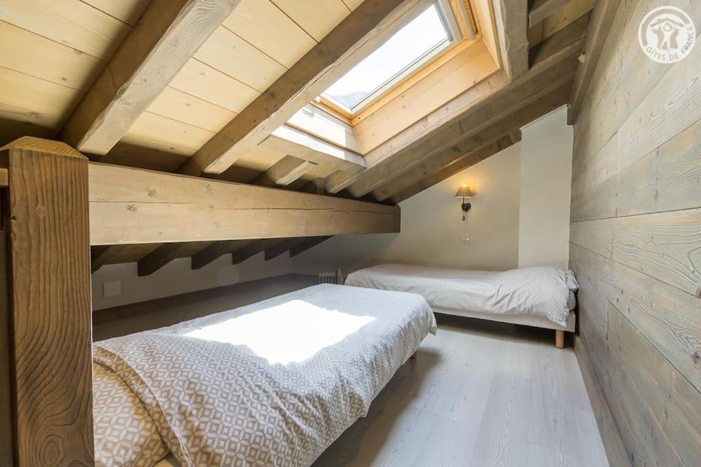 a attic bedroom with two beds and a window at Chalet Bio Corti 6p. 3 ch proche pistes&#47;commerces in Champagny-en-Vanoise