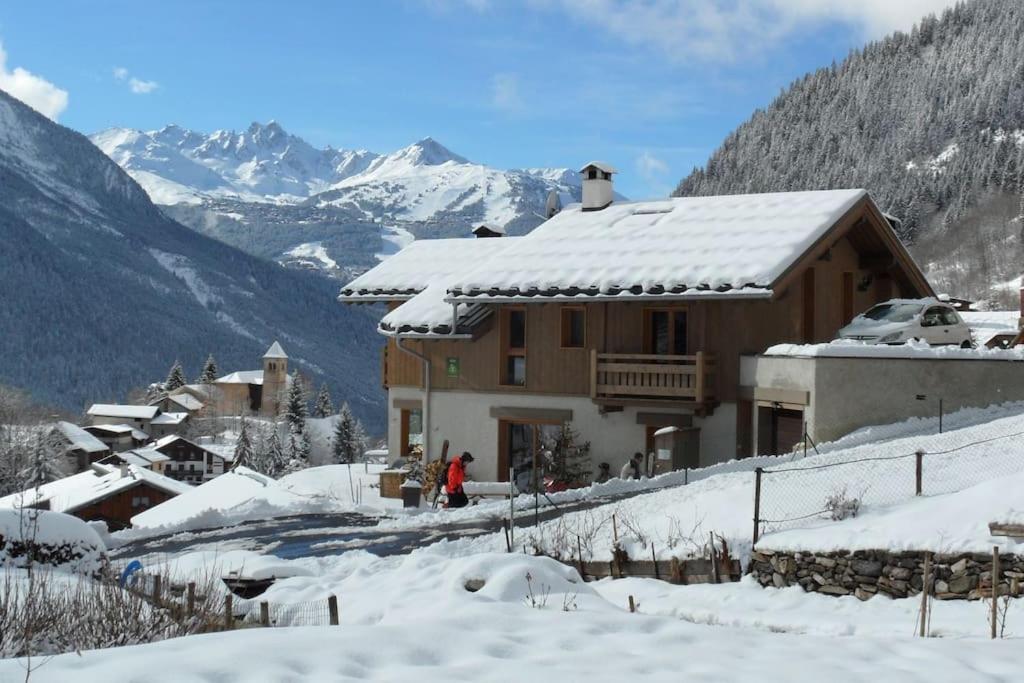 a house covered in snow with mountains in the background at Chalet Bio Corti 6p. 3 ch proche pistes&#47;commerces in Champagny-en-Vanoise