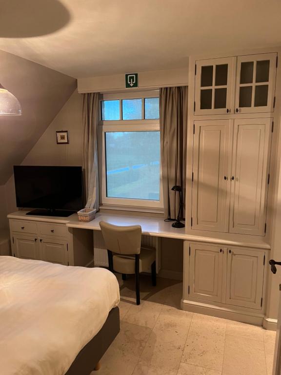 a bedroom with a bed and a desk with a window at B&amp;B - Ter Douve in Dranouter