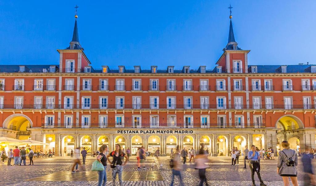 un grand bâtiment avec des personnes qui marchent devant lui dans l'établissement Pestana Plaza Mayor Madrid, à Madrid