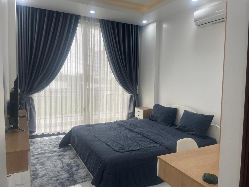 um quarto com uma cama azul e uma grande janela em Thanh An Homestay&Guesthouse em Hue