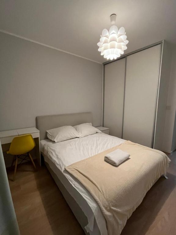 a bedroom with a white bed and a yellow chair at airport cybernetyki2 inn in Warsaw