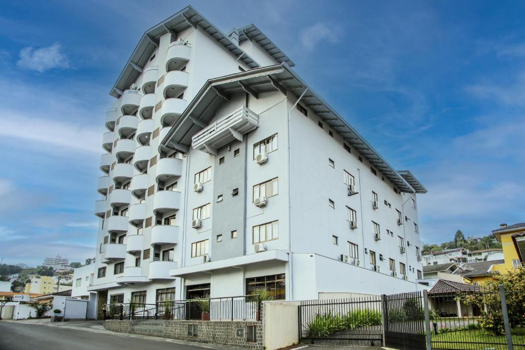 a white building with windows on a street at Hotel das Videiras in Videira